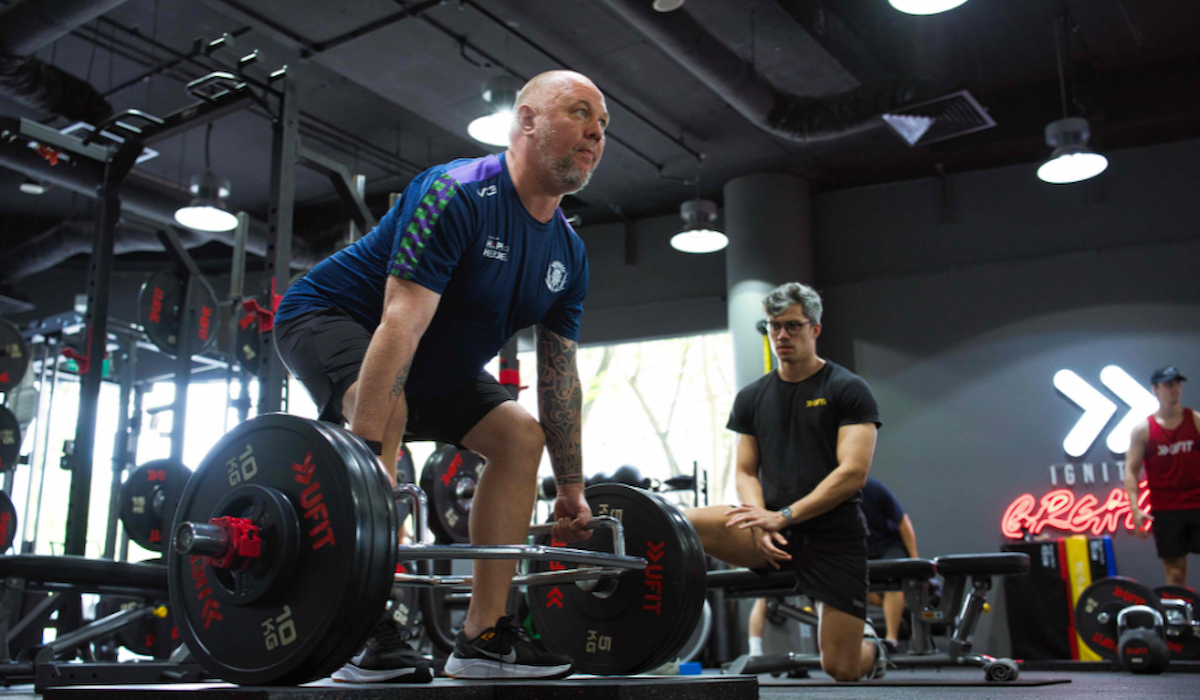 Man doing Trap bar deadlift with personal trainer