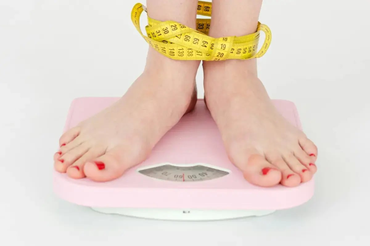 Weighing scale & measuring tape on leg - weight loss image